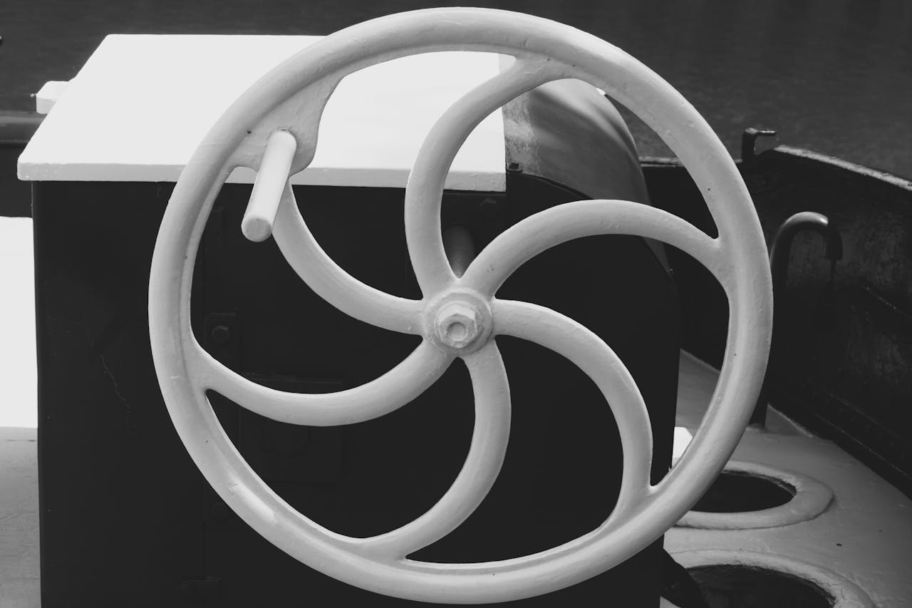 Grayscale close-up of a vintage nautical steering wheel in Gent, Belgium.